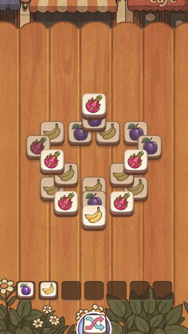 Juicy Cafe Match mid-level board: stacked layers of fruit tiles around a ring layout with two tiles already collected in the bottom tray and the level and coin HUD above
