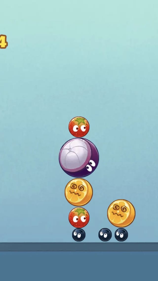 Merge Watermelon gameplay showing the score at the top left and a pile of cartoon-faced fruits - blueberries, strawberries, a purple mangosteen and yellow lemons - stacked on the ground line