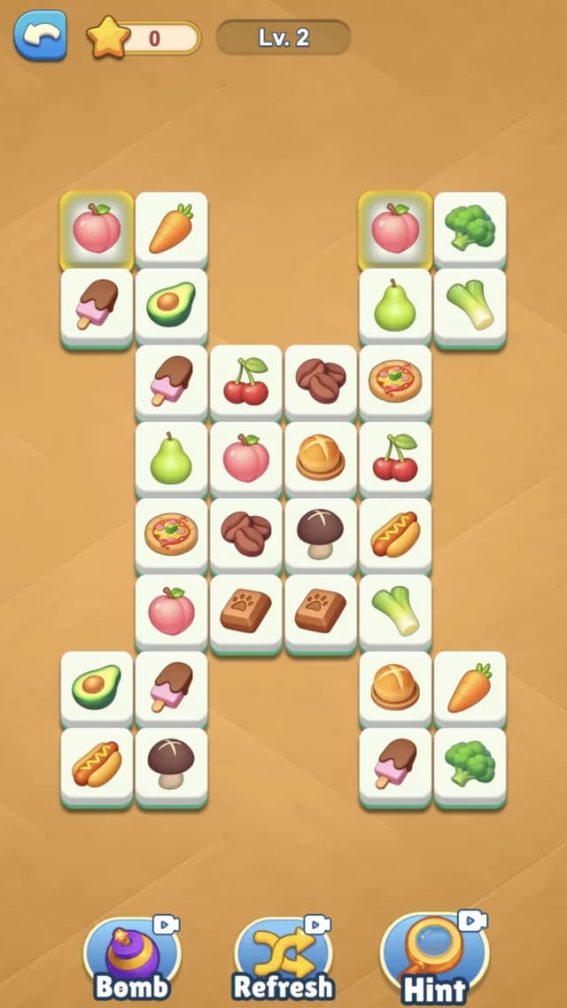 Level two connect-two board in Tile Makeover Story with thirty-two food-icon tiles and the booster bar along the bottom